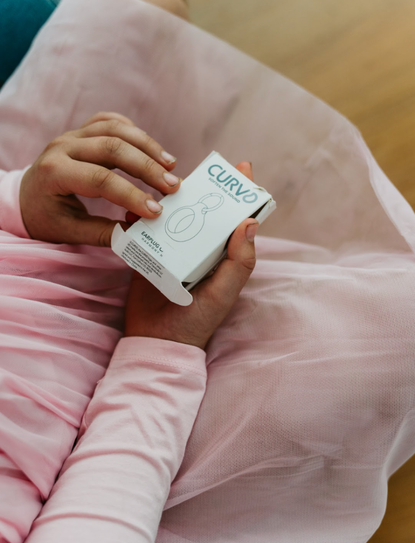 Child's hands hold a white Curvd earplug case by The Play Way, a compact tool for on-the-go sensory support.