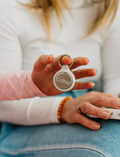 Hands hold a white Curvd earplug case on a keychain from The Play Way, ideal for portable sensory regulation.