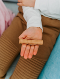 Child's hand holding a ribbed Sensory Play Australia Wooden Fidget, a natural wood tool for sensory and emotional regulation.