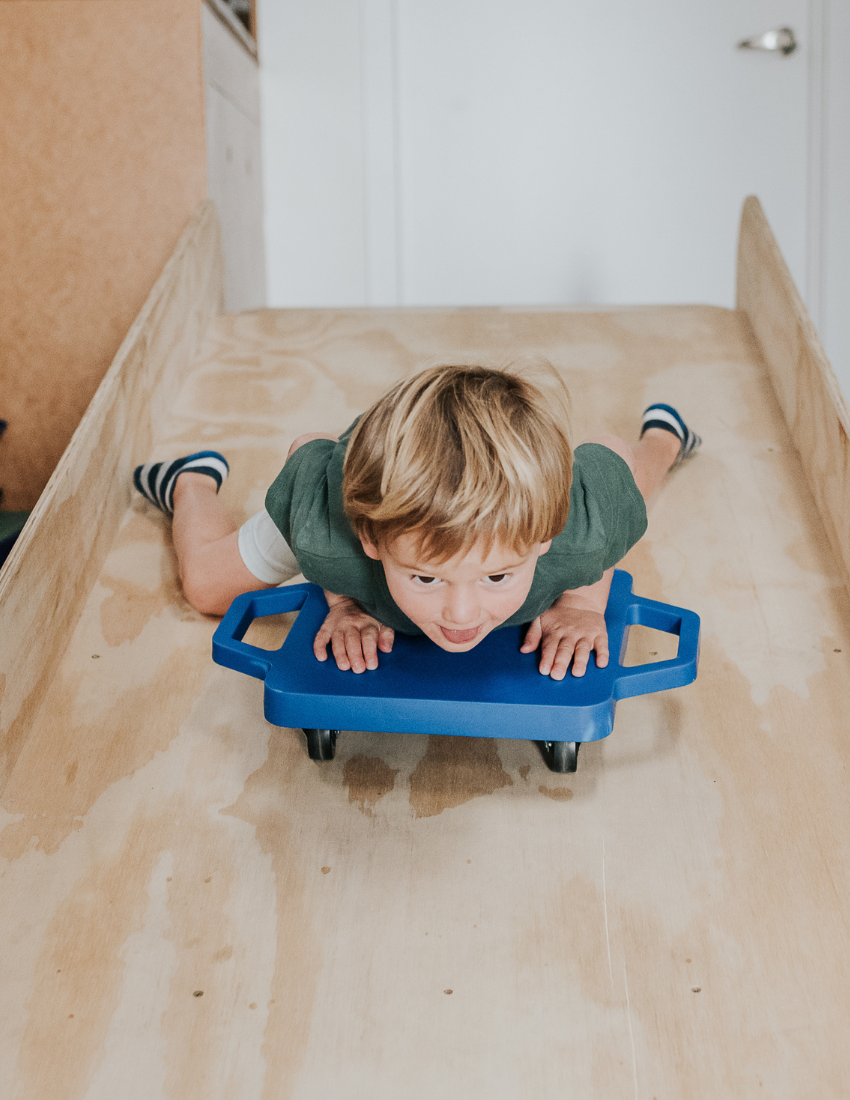 Yellow scooter board by The Play Way, a therapist-designed tool for promoting physical development and motor skills in kids.