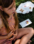 A young girl practices mindful breathing outdoors with Sensory Play Australia cards, a 'Balloon' card visible, promoting kids' calm & focus.
