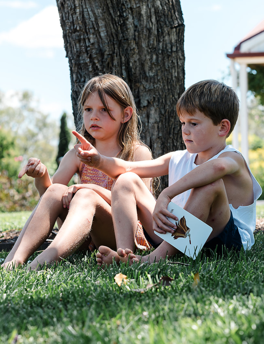 Two children outdoors with The Play Way Regulation Card Set Bundle's therapist-designed sensory play card, fostering nature exploration and emotional regulation.