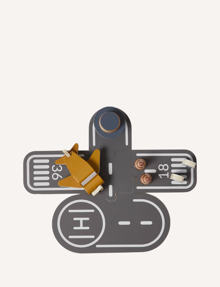 Top view of a wooden toy airport playset with airplane and runway pieces.