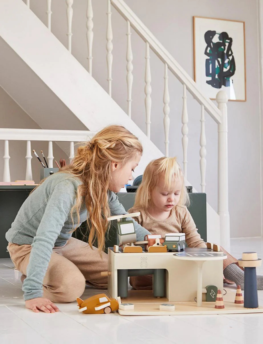 Two children playing with a wooden toy parking garage and vehicles.