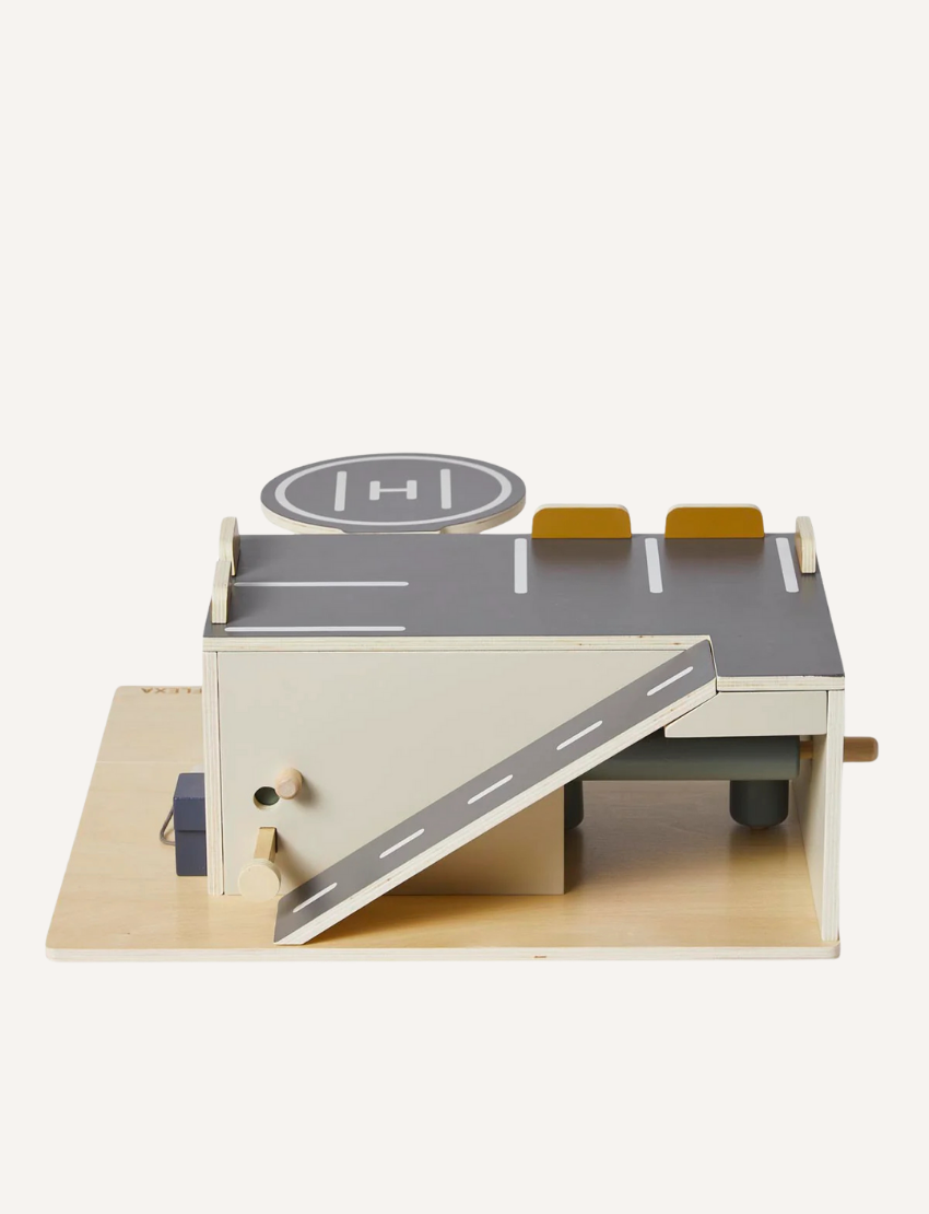Wooden toy parking garage with ramp, helipad, and charging station from a side angle.