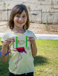Smiling girl holding the Mrs Green Pocket Press, showcasing her love for nature crafts and outdoor activities.