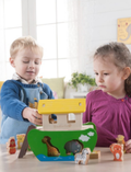 Two children playing with a wooden Noah's Ark shape-sorting toy with animal figures.