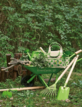 Children's green wheelbarrow loaded with gardening tools, a watering can, and natural elements for outdoor fun.