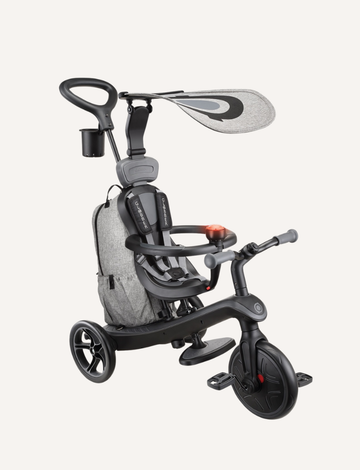 The Globber EXPLORER Trike 4 in 1 DELUXE PLAY in Black/Grey is a children's tricycle equipped with a canopy, safety harness, and rear push handle. It includes features like a cup holder, a three-wheel design, and a small storage bag at the back.