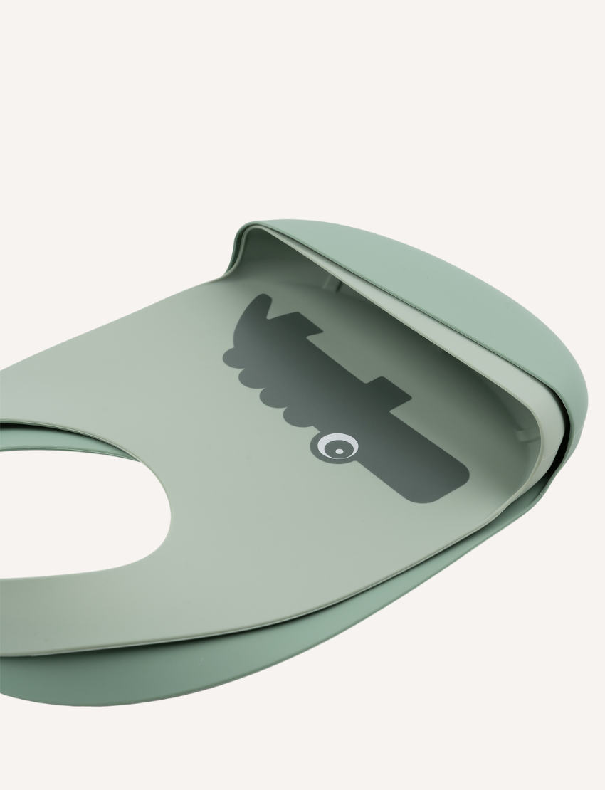 Two light green silicone baby bibs, one with a crocodile print and the other with small flies.