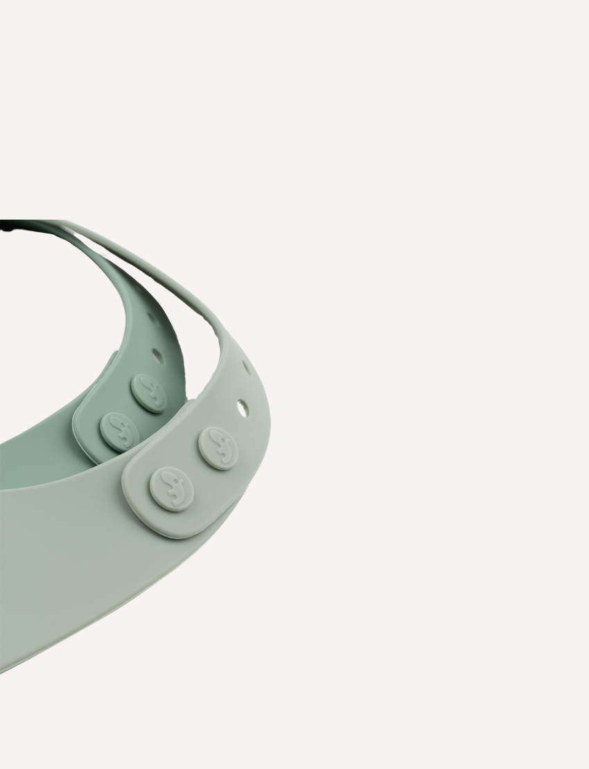 Close-up view of the adjustable snap closure on a light green silicone baby bib.