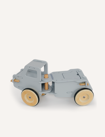 The Classic Dump Truck by Moover is a light gray wooden toy with smooth edges and large wheels, crafted using the Moover click system. Its simple design helps children develop gross motor skills, set against a plain white backdrop for minimalist appeal.