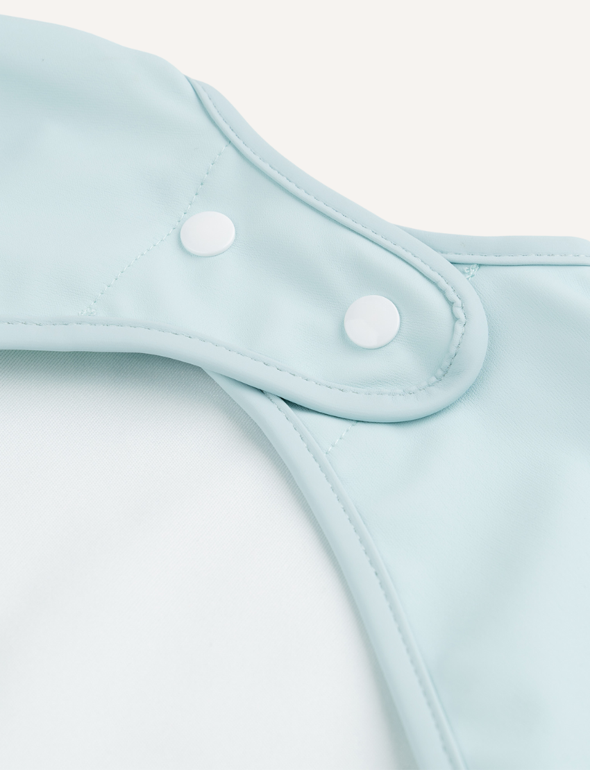 Close-up of light blue baby bib with snap closure for neck fastening.