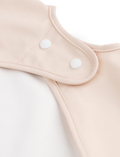 Close-up of powder pink baby bib with snap closure for neck fastening.