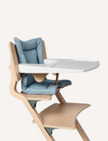 A light blue cushion set on a wooden high chair with a white detachable tray.