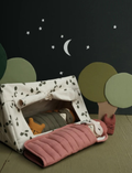 A camping scene with a patterned tent, dolls in sleeping bags, and stylized trees under a night sky.