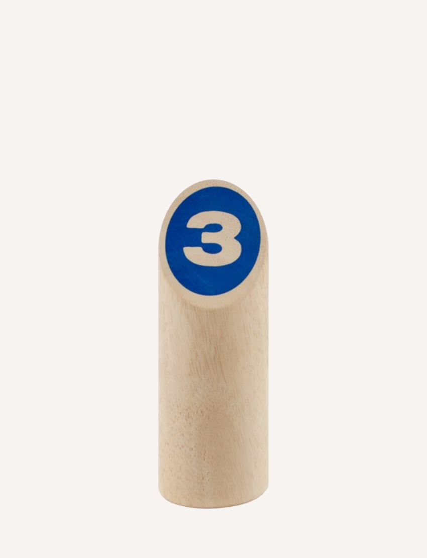 Close-up of a wooden pin with a blue circle and the number '3' for a toss game.