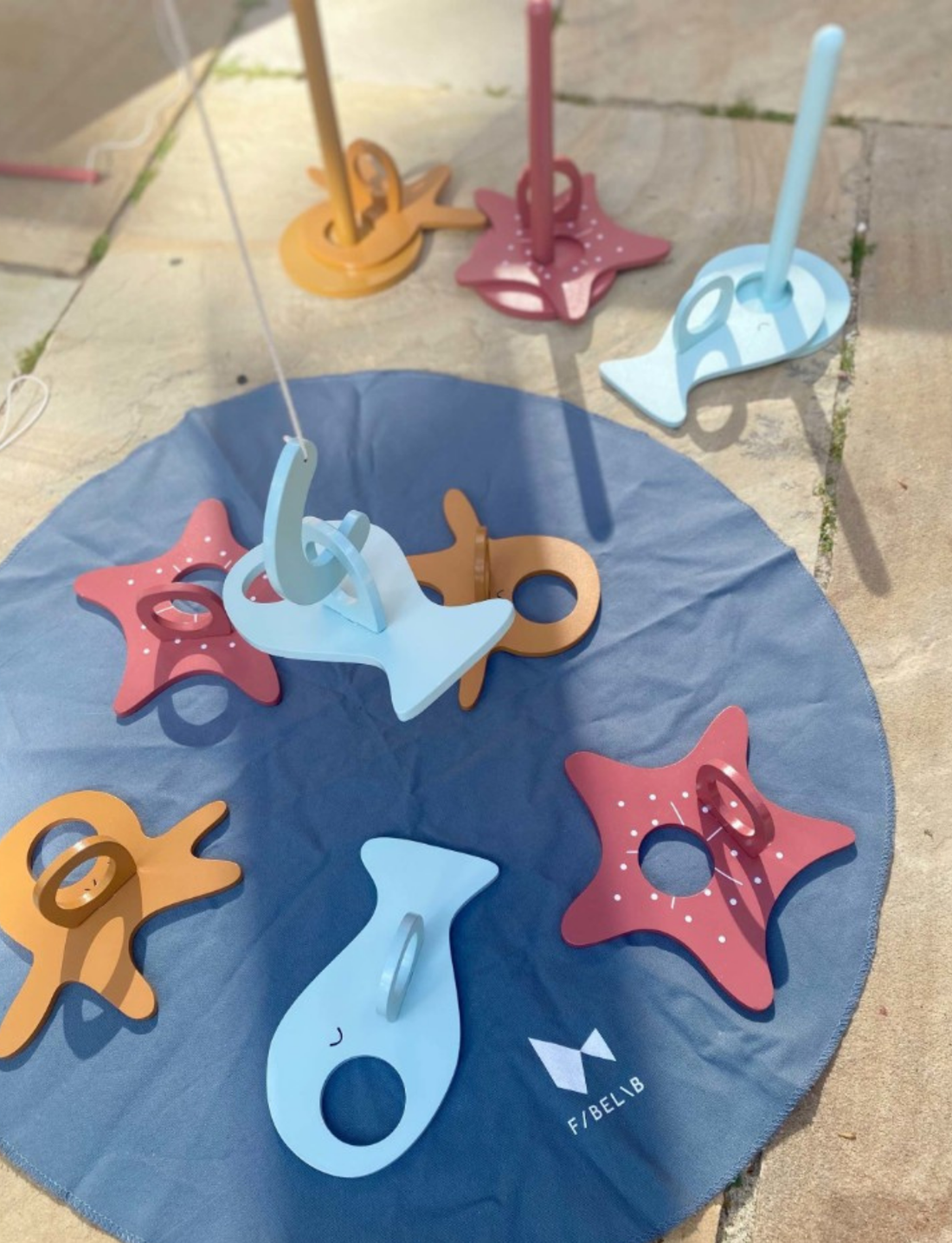Overview of a wooden magnetic fishing game set on a dark blue play mat, featuring fish and stars.