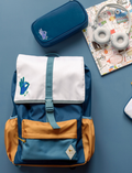 Blue backpack with white flap and blue OK hand logo, next to blue pencil case & headphones.