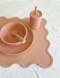 Dusty rose silicone dinner set for babies: a scalloped placemat, plate, bowl, cup with straw, and spoon.