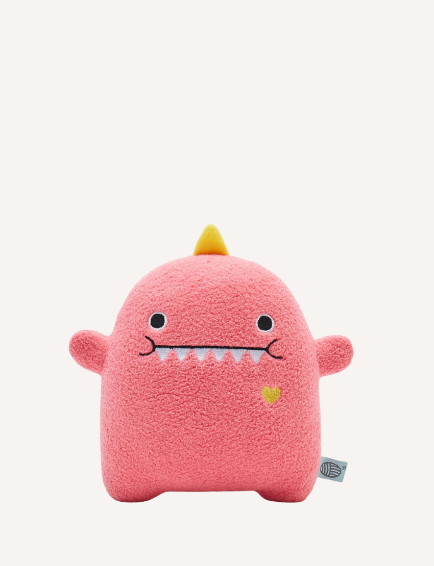 Pink plush dinosaur toy with embroidered face, yellow spikes, and a small yellow heart.