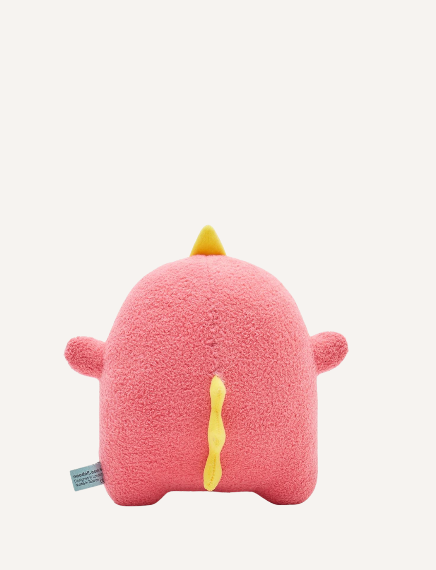 Pink plush dinosaur toy with embroidered face, yellow spikes, and a small yellow heart.