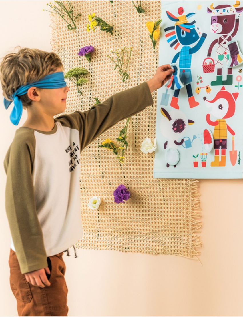 A boy with a blue blindfold on attempts to pin a fabric tail onto a character in a "Pin the Tail" game.
