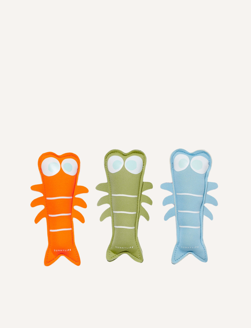 Three colorful shrimp-shaped Sunnylife Dive Buddies pool toys in orange, green, and blue. Soft weighted plush for water fun.