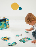 Toddler playing with dinosaur puzzles and a Janod puzzle box in a bright, airy room.