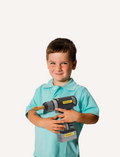 Boy smiling holding a Stanley Jr. toy drill with a wooden bit, part of a tool set.