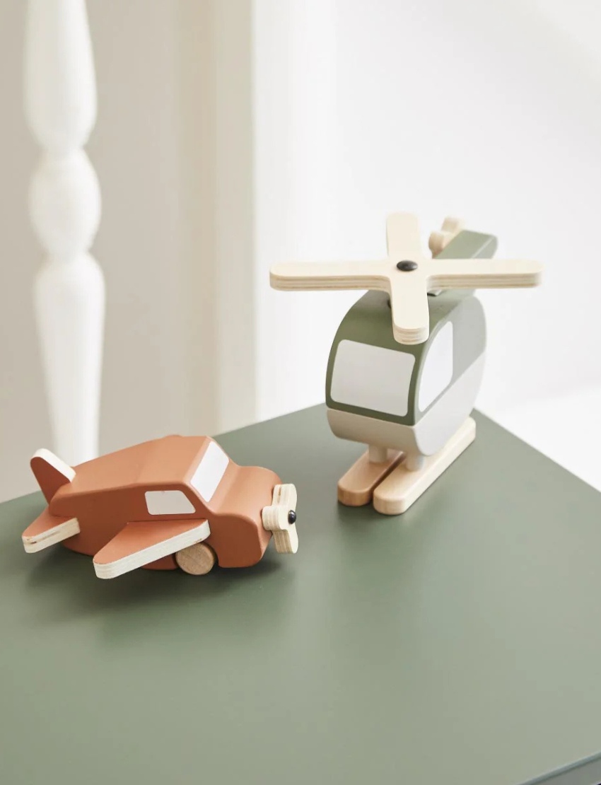Green and brown wooden helicopter toy and brown airplane toy displayed on a white background.