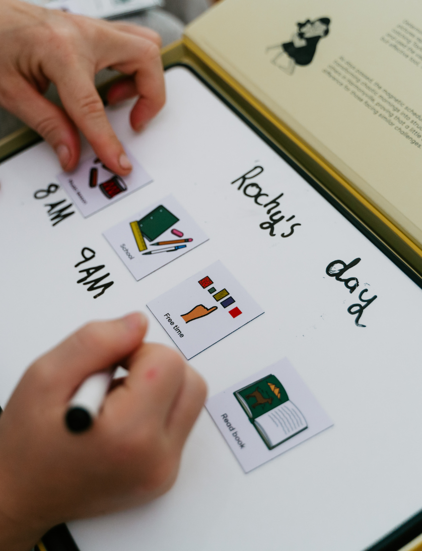 Close-up of hands placing Sensory Play Australia visual cards on a whiteboard, a therapist-designed tool for Rocky's daily routine.