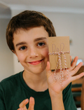 Smiling boy holding a small brown paper gift box tied with twine, labeled