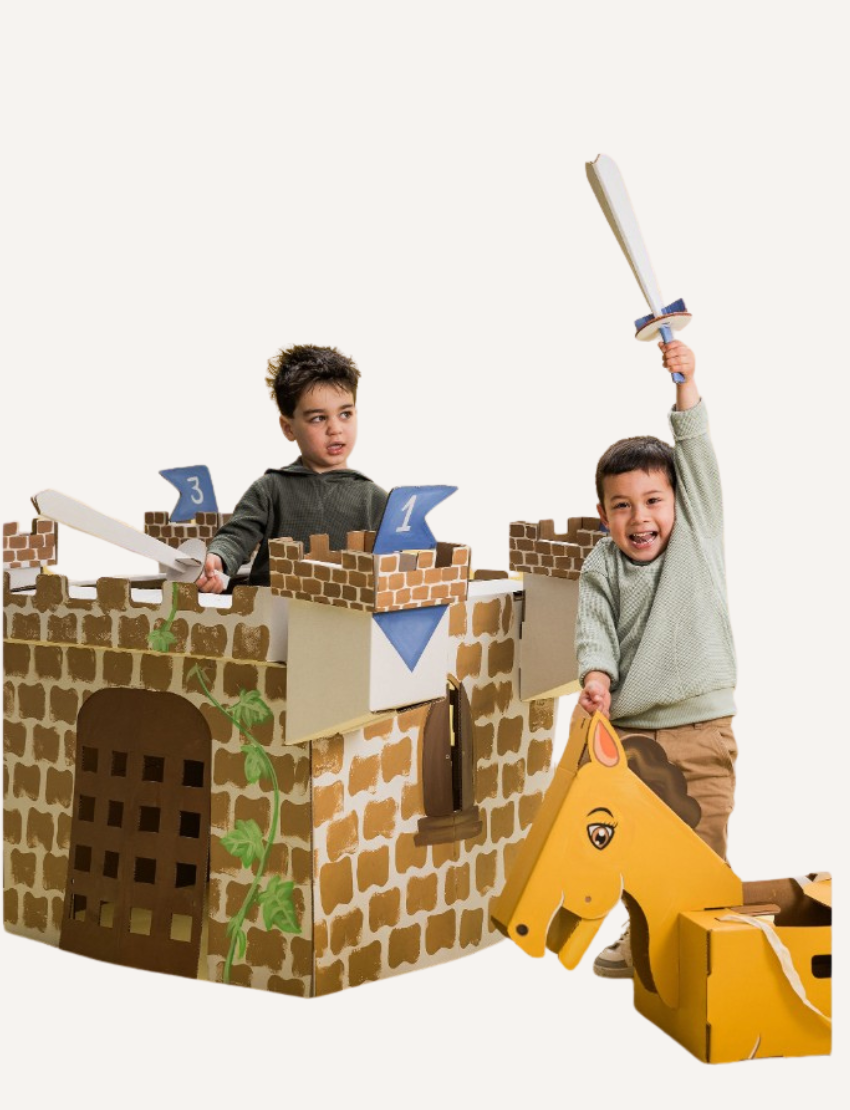Two young boys playing with a cardboard castle and horse costume, one holding a toy sword.