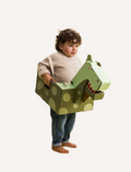 Young boy wearing a green dinosaur cardboard costume with polka dots, holding it up.
