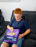 Young boy with red hair and freckles opening the CircuitMess Sparkly robot car kit box.