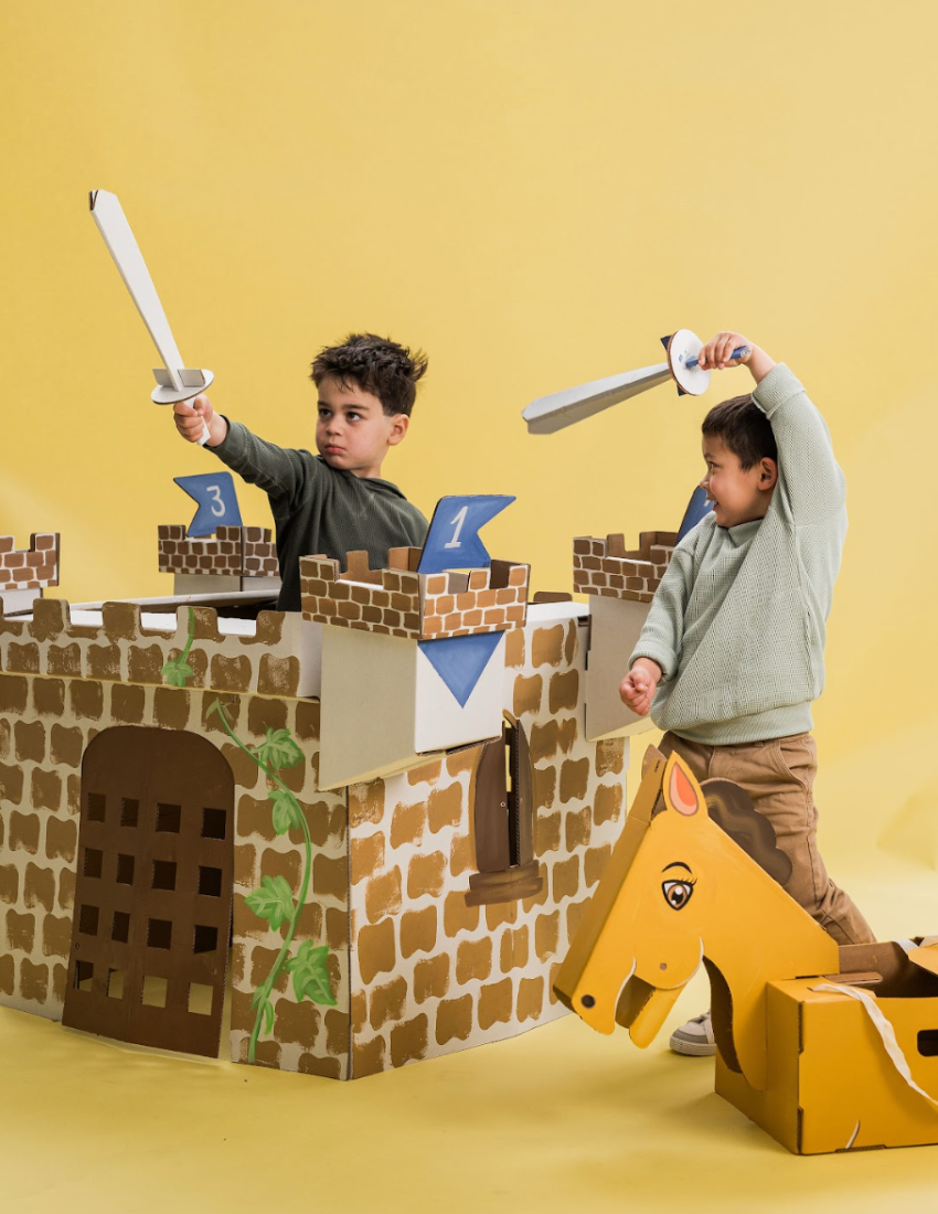 Cardboard castle kit and horse with 'Noble Knight' activity book, displayed overflowing from a teal box.