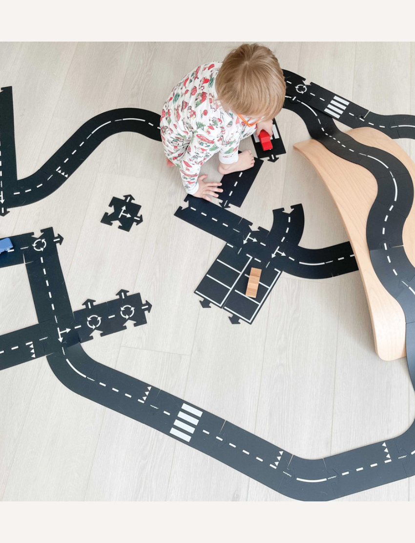 Way to Play 'King of the Road' toy race track with cars and a child playing. Flexible road construction toy for endless play.