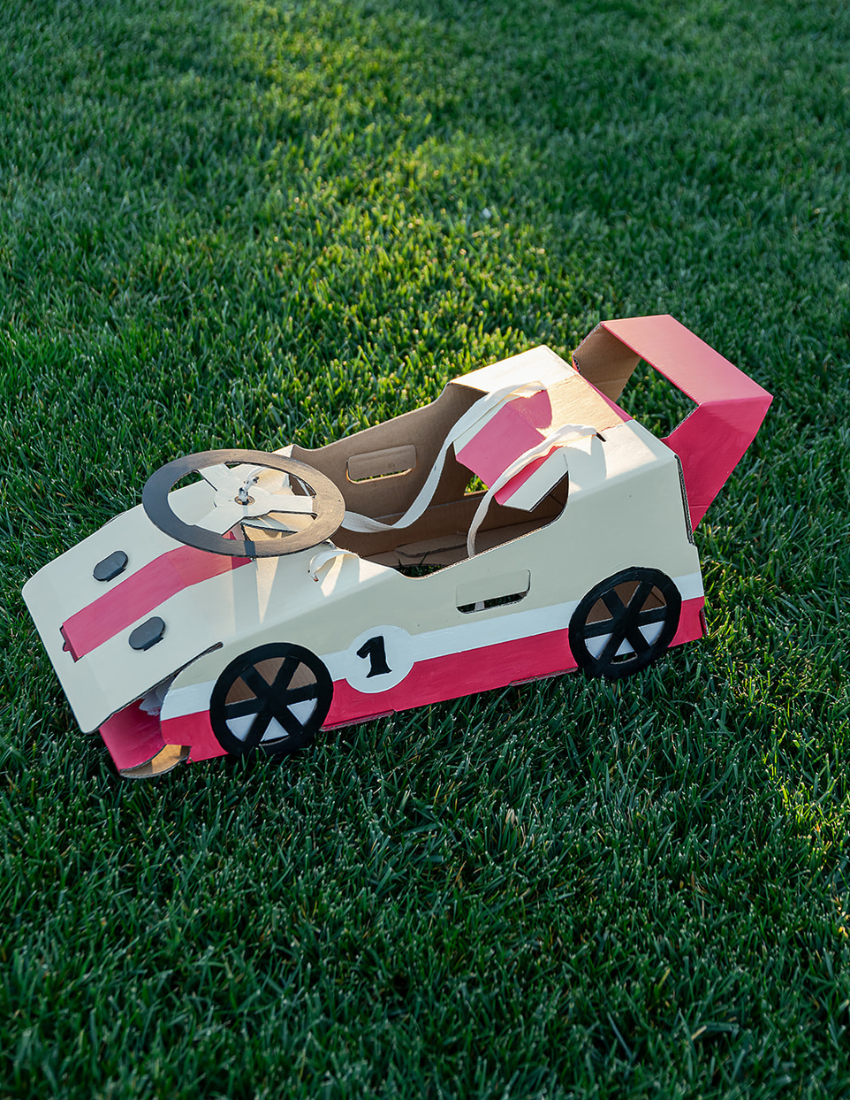Cardboard 3D transport models including cars and a helicopter, with a booklet, partially in a box.