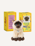 Plush Siamese cat sitting in front of yellow packaging boxes resembling sardine cans.