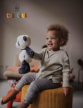Smiling toddler sitting on a yellow ottoman holding a plush panda, with 'WWF CUB CLUB' logo.