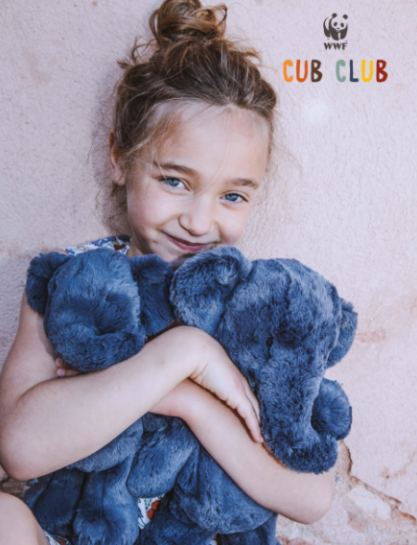 Young girl with blue eyes and messy bun hugging a plush dark grey elephant.