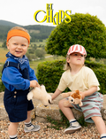 Two adorable children enjoying Chaps Mail plush toys outdoors in a natural setting.