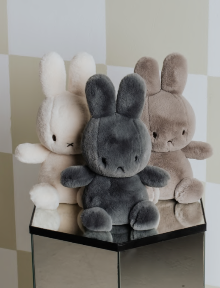 Two cute Miffy plush toys, one cream and one grey, sitting side-by-side on a neutral background.