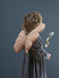 Child from behind wearing dusty rose fairy wings and holding a wand, with curly hair.