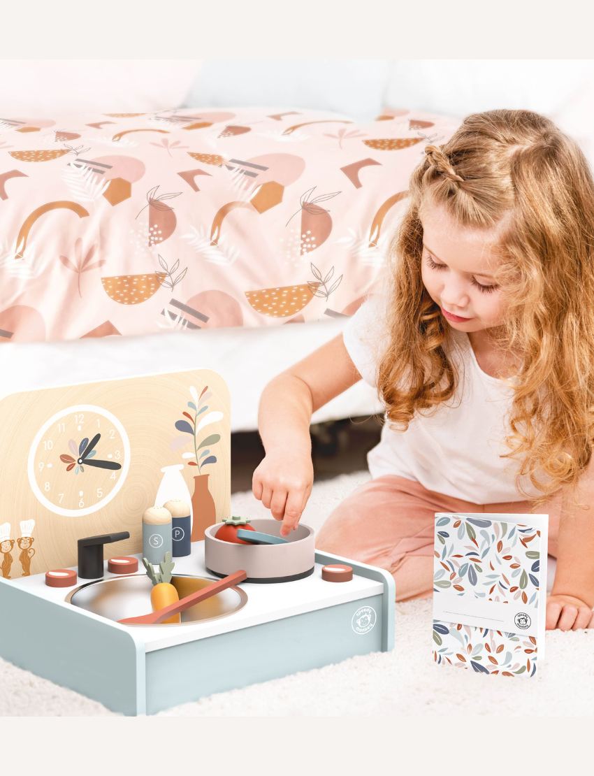 Speedy Monkey wooden table kitchen playset with accessories including pots, pans, food, and clock, promoting imaginative play.