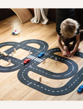 Child playing with a wooden car and track set on a wooden floor.