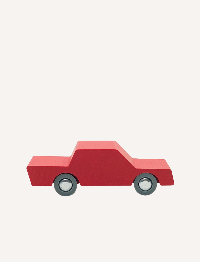 Red wooden toy car with grey wheels on a plain background.