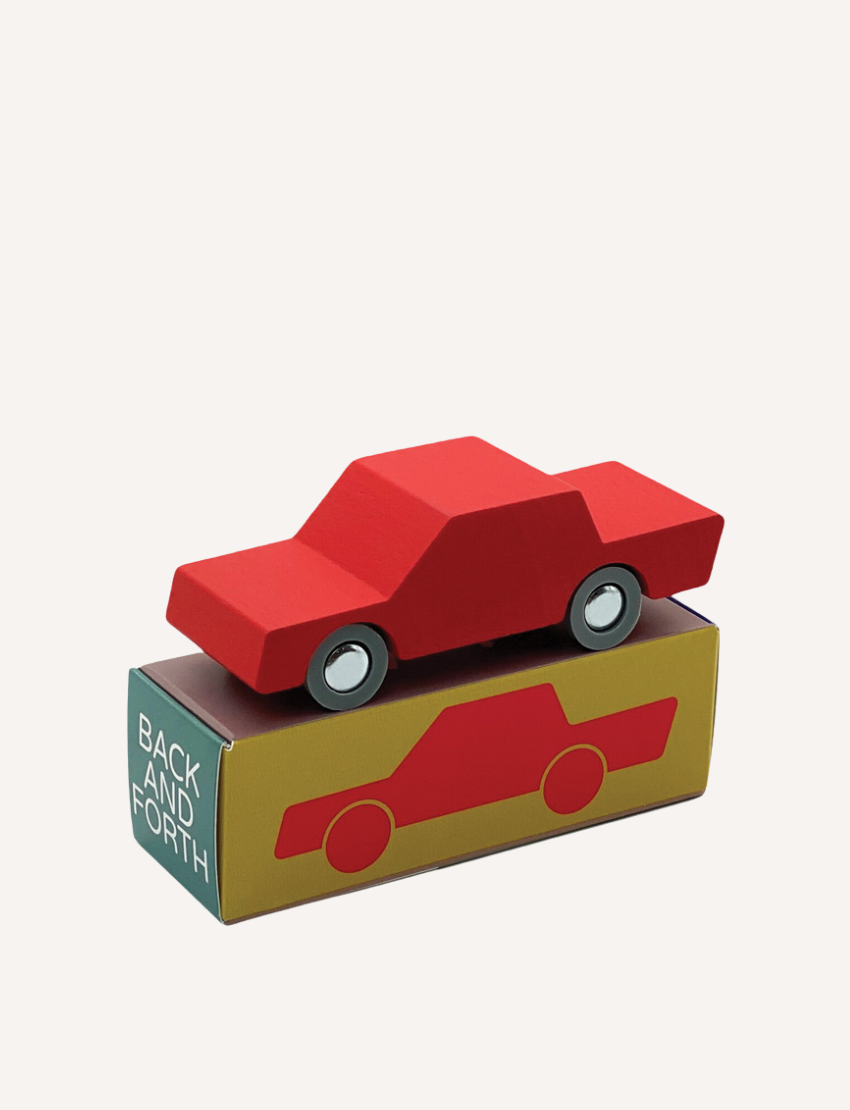 Red wooden toy car resting on its branded product packaging.