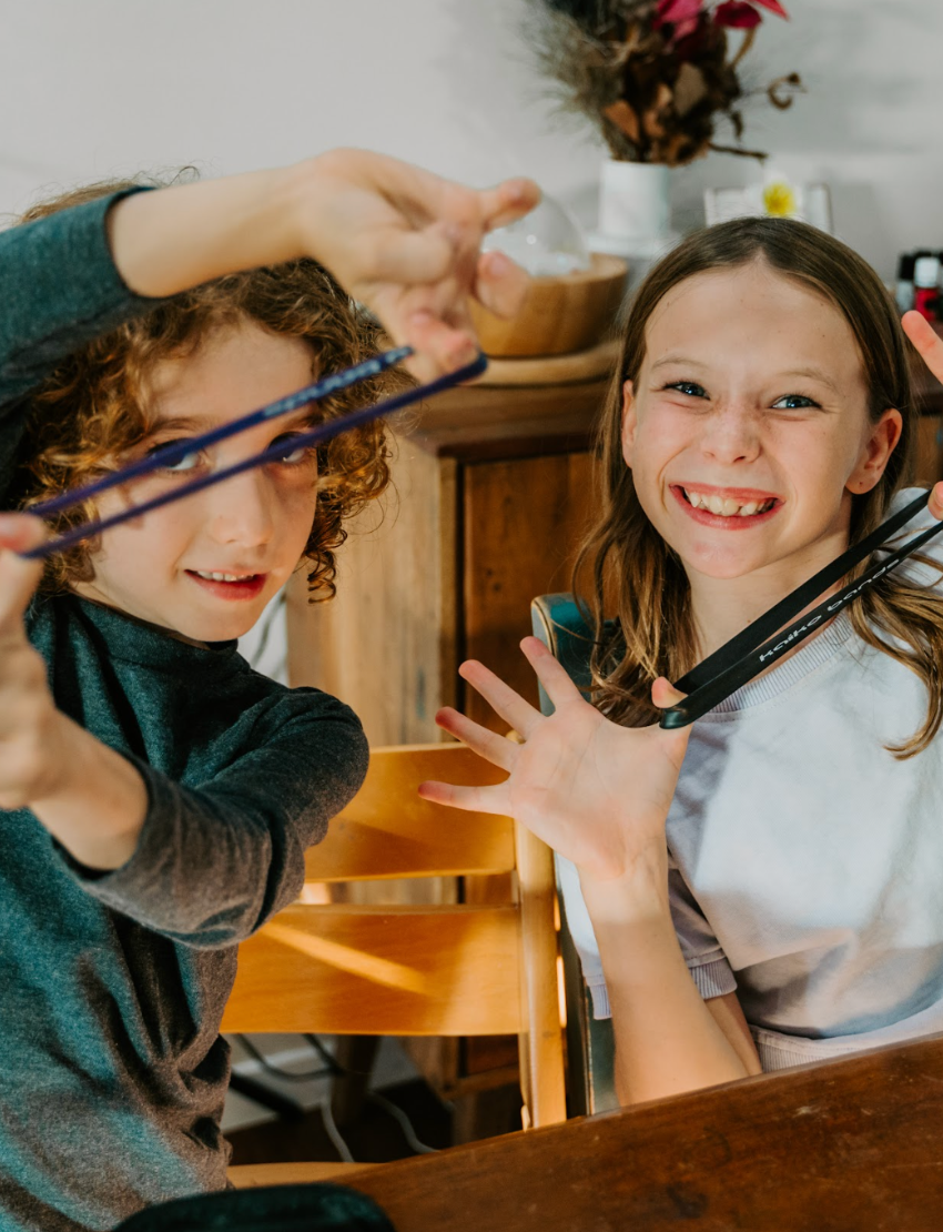 Two children happily stretch resistance bands from The Play Way's therapist-designed Regulation Preferences Kit for sensory input.